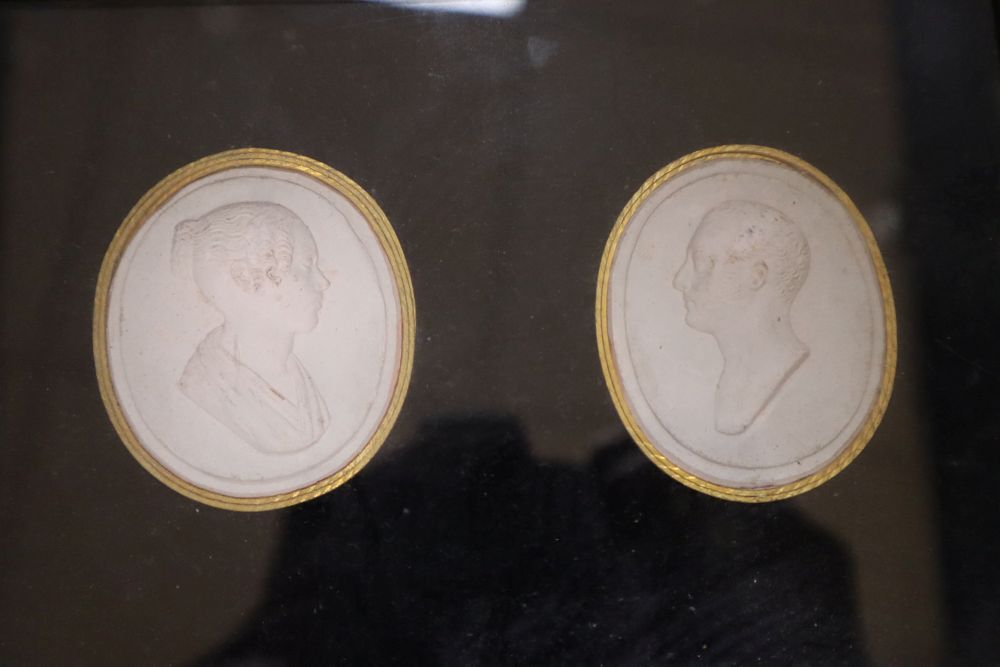 A collection of intaglio relief portrait plaques in a tray and a pair of framed sets